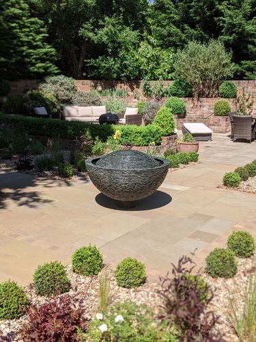 1.2m Grey Semi-sphere on a small raised slate pedestal set centrally on this generous patio. 